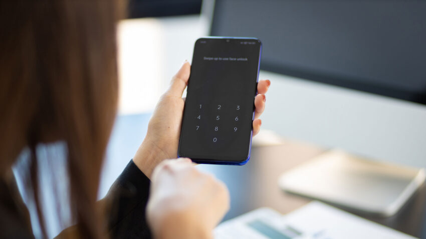 Persoon kijkt naar een telefoon om in te loggen.