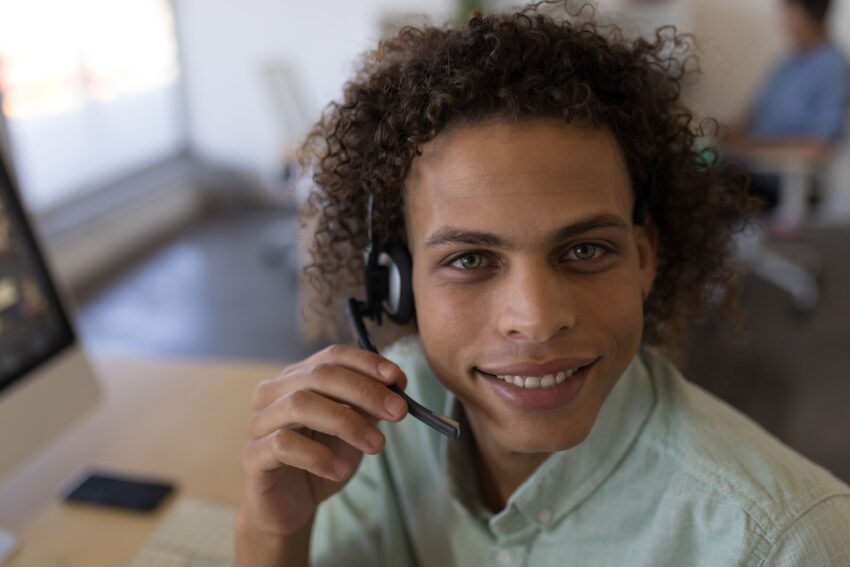 Portret van een mannelijke bewindvoerder met headset aan een bureau op kantoor
